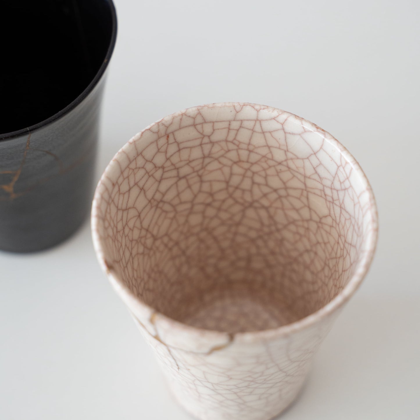 Hvid keramikkop repareret med kintsugi, en traditionel japansk kunst at reparere knust keramik med guldlak