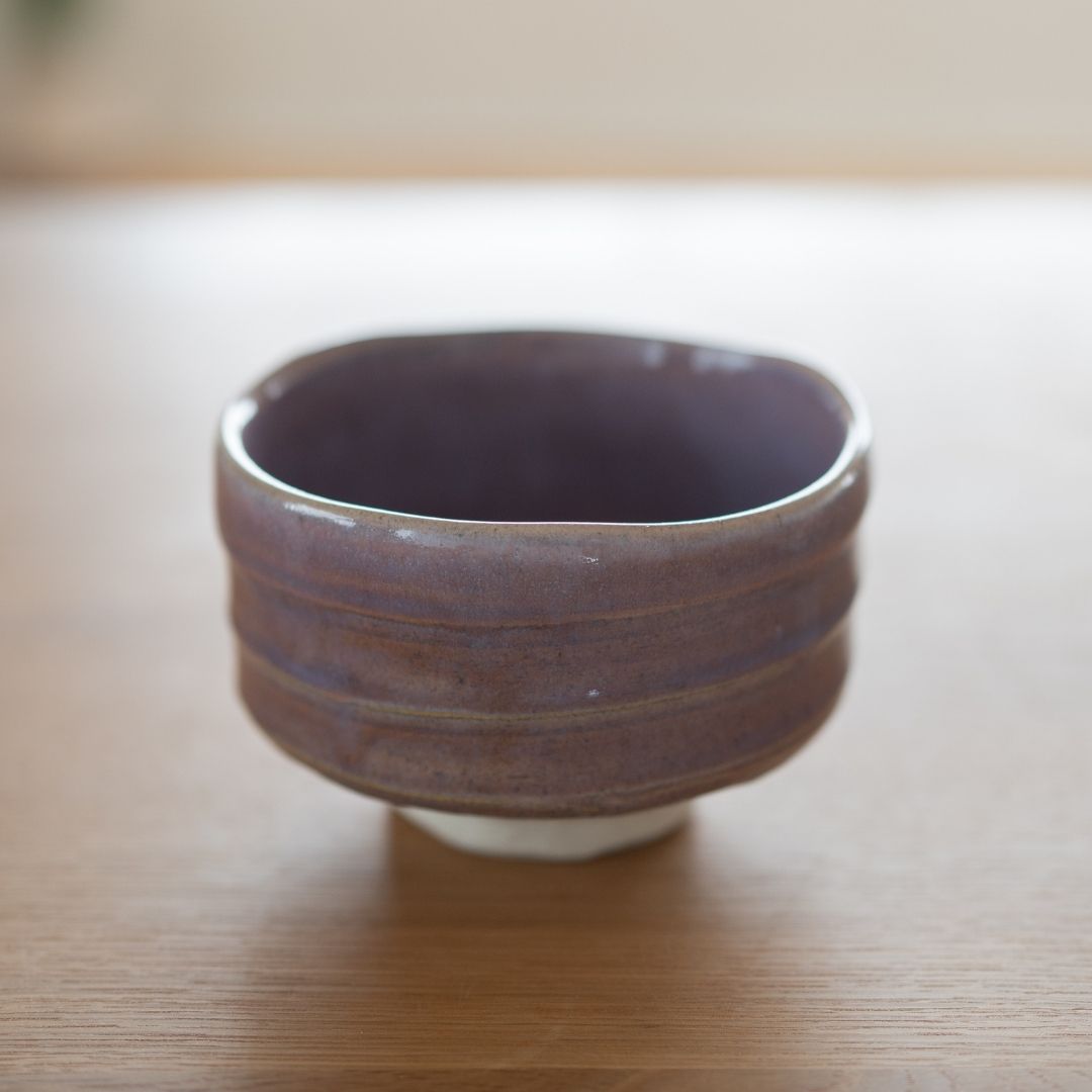 Detaillierte Textur einer japanischen Matcha-Schale aus blassem violettem Mino-Keramik, die den Shino-Ton hervorhebt, der durch die fließende hellviolette Glasur scheint, charakteristisch für die Chawan des Shinzan-Brennofens.