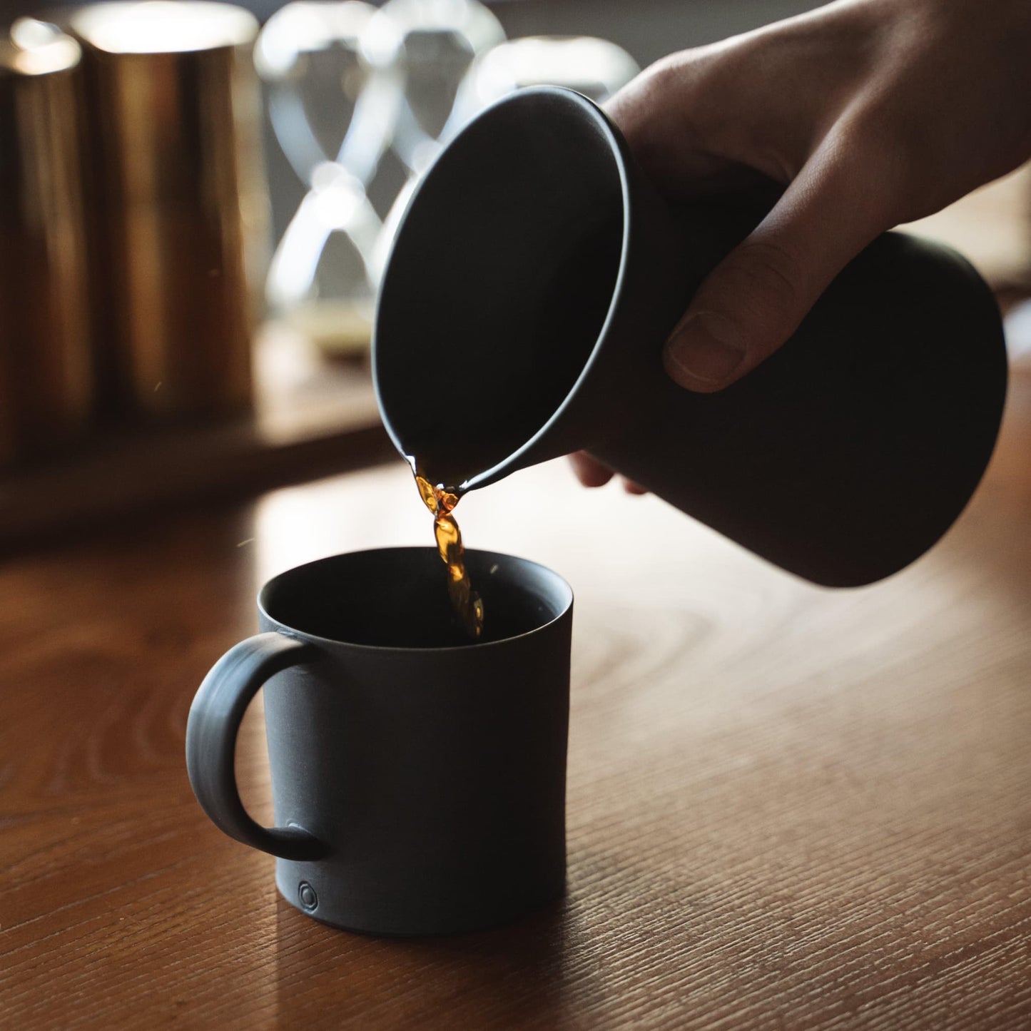Hælder kaffe fra en minimalistisk sort Banko stel kaffekande op i en sort kop.