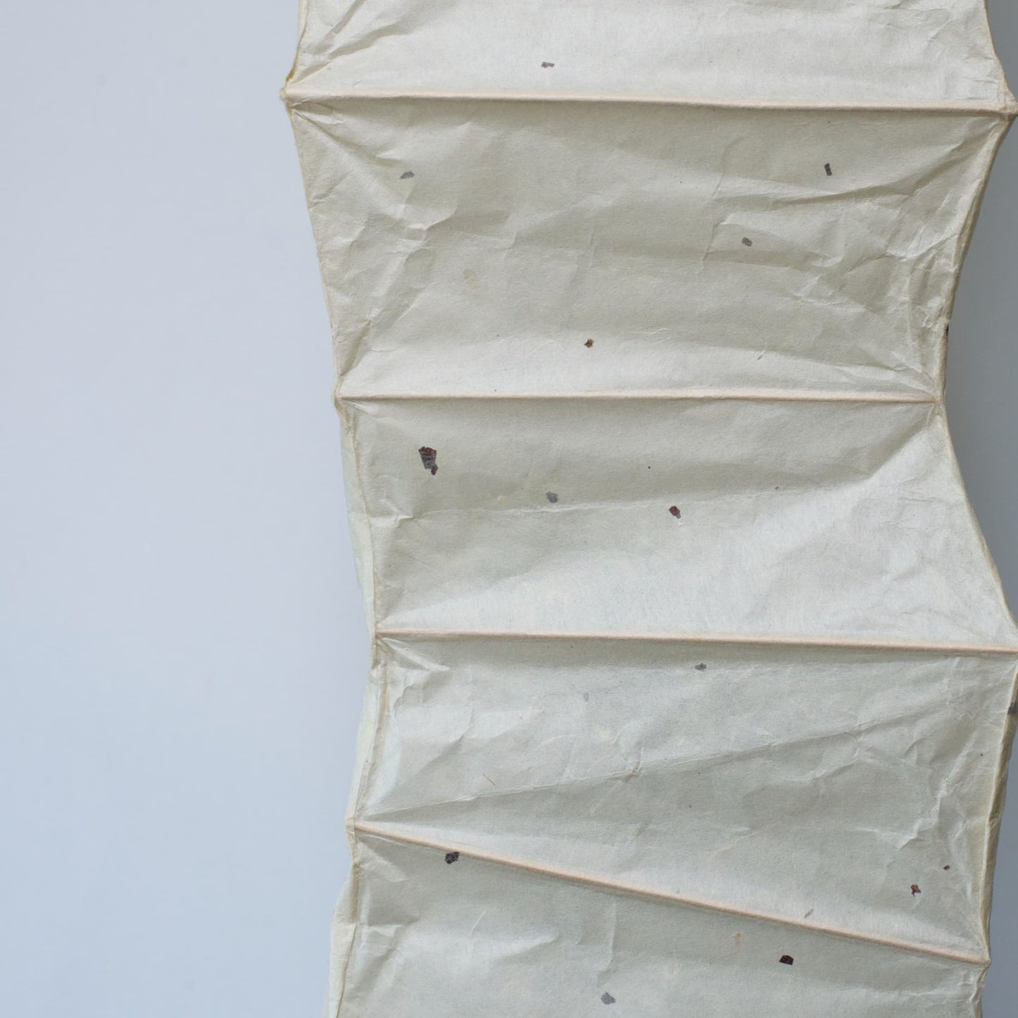 "Vue latérale détaillée d'une lampe incurvée en papier japonais washi sur fond blanc, mettant en valeur les motifs du washi"
