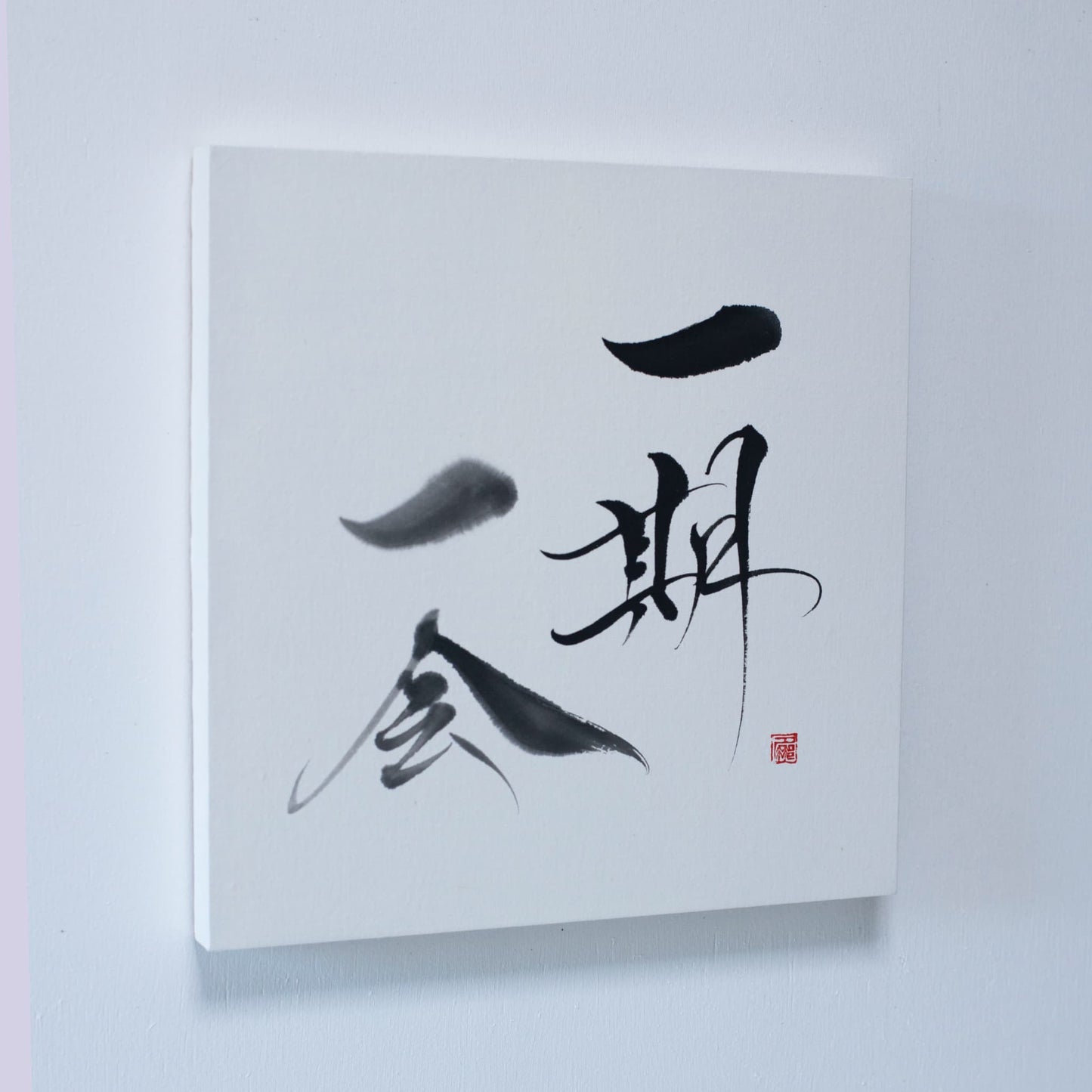 "Une estampe représentant « Ichigo Ichie » en calligraphie japonaise, montée sur un mur blanc." 