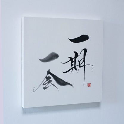 "Une estampe représentant « Ichigo Ichie » en calligraphie japonaise, montée sur un mur blanc." 