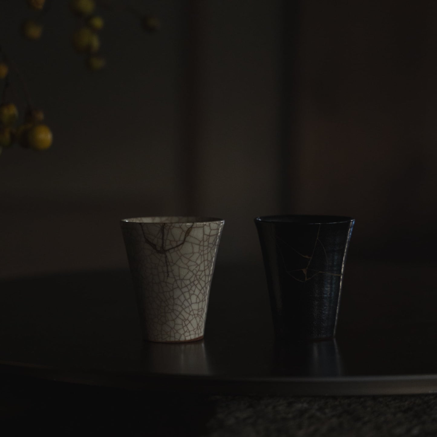To Kintsugi-kopper på sort bord: "Vermilion Crackle 01" & "Jet Black Lightning"