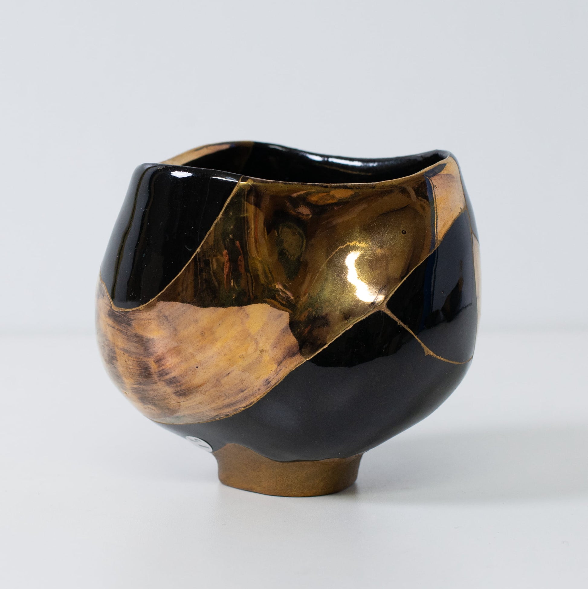 Vue de côté d'un bol en poterie kintsugi avec des lignes de réparation dorées et un émail à fort contraste