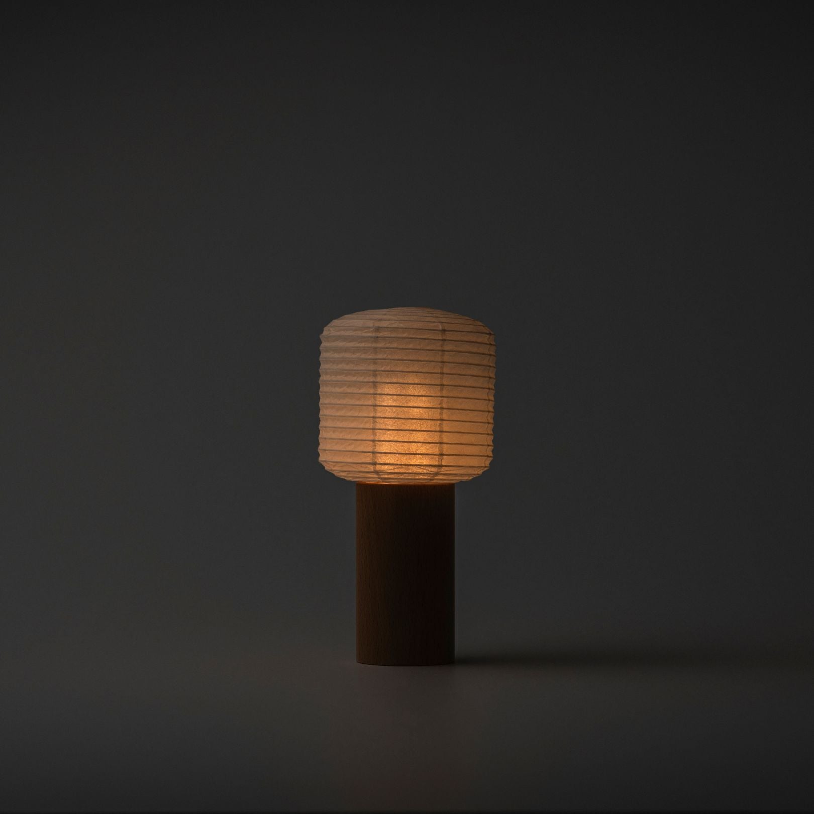 Eine tragbare Papierlampe, die in einem dunklen Raum sanft mit warmem Licht leuchtet, mit einem Holzgriff und einer Papierhaube