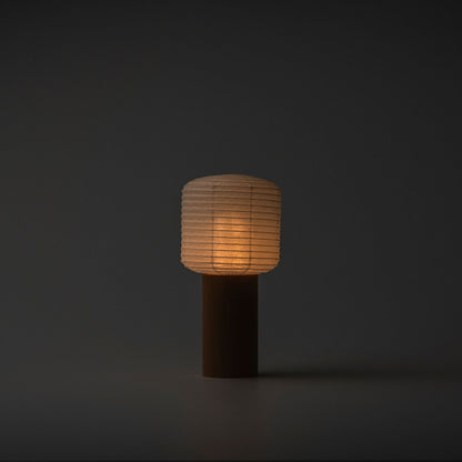 Eine tragbare Papierlampe, die in einem dunklen Raum sanft mit warmem Licht leuchtet, mit einem Holzgriff und einer Papierhaube