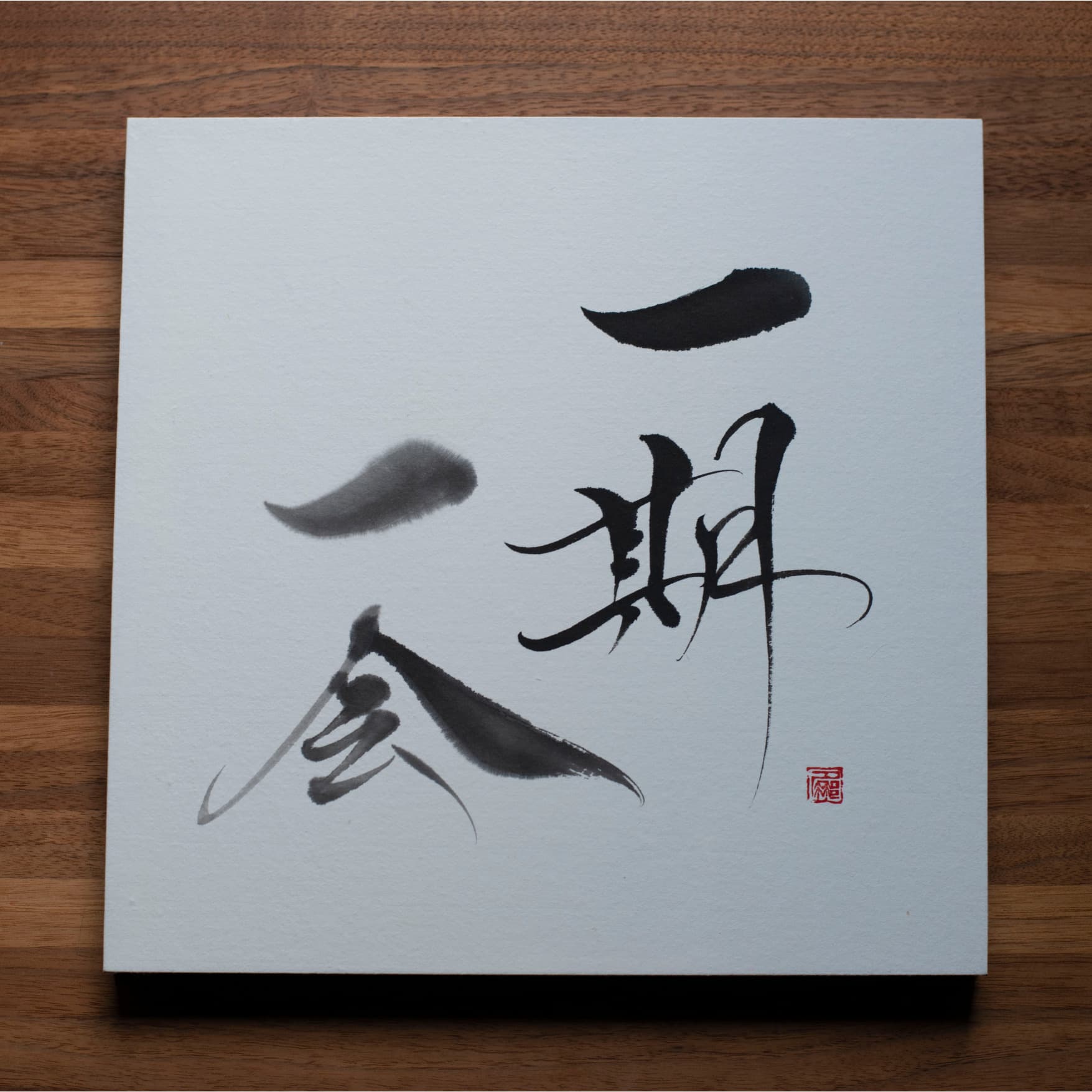 Vue_du_dessus_d_un_panneau_de_calligraphie_avec_Ichigo_Ichie_sur_une_table_en_bois