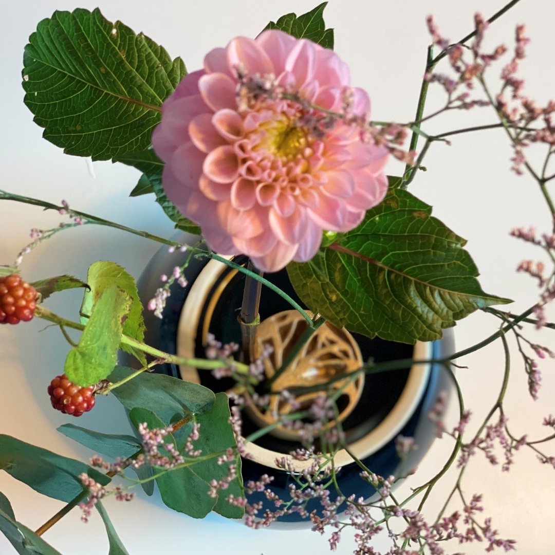 Topudsigt over ikebana blomsterarrangement i japansk vase med pindløs kenzan, ginkgoen