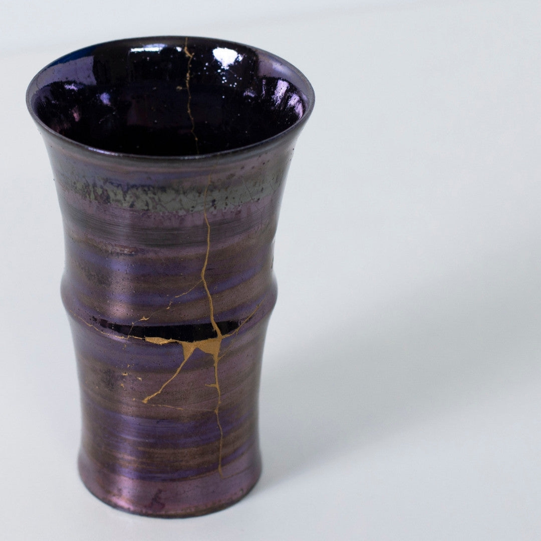 Top view af blank lilla kintsugi-kop med dramatisk gylden revne | wabi sabi keramik