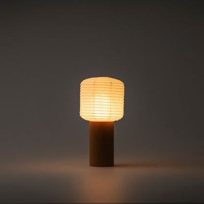alt
Eine tragbare Yame-Laterne mit Holzsockel und Papierabdeckung, die in einem dunklen Raum helles warmes Licht abgibt