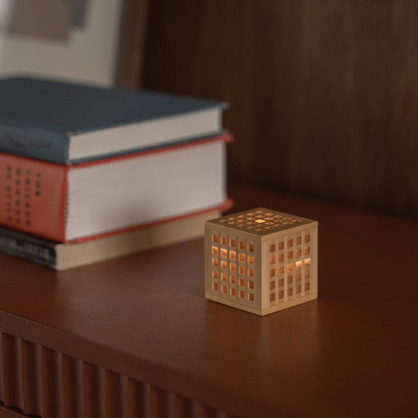 Japanische Mini-Holzlampe "Hotaru", die warmes Licht neben Büchern als schnurlose japanische Tischlampe und Akzentlampe wirft.