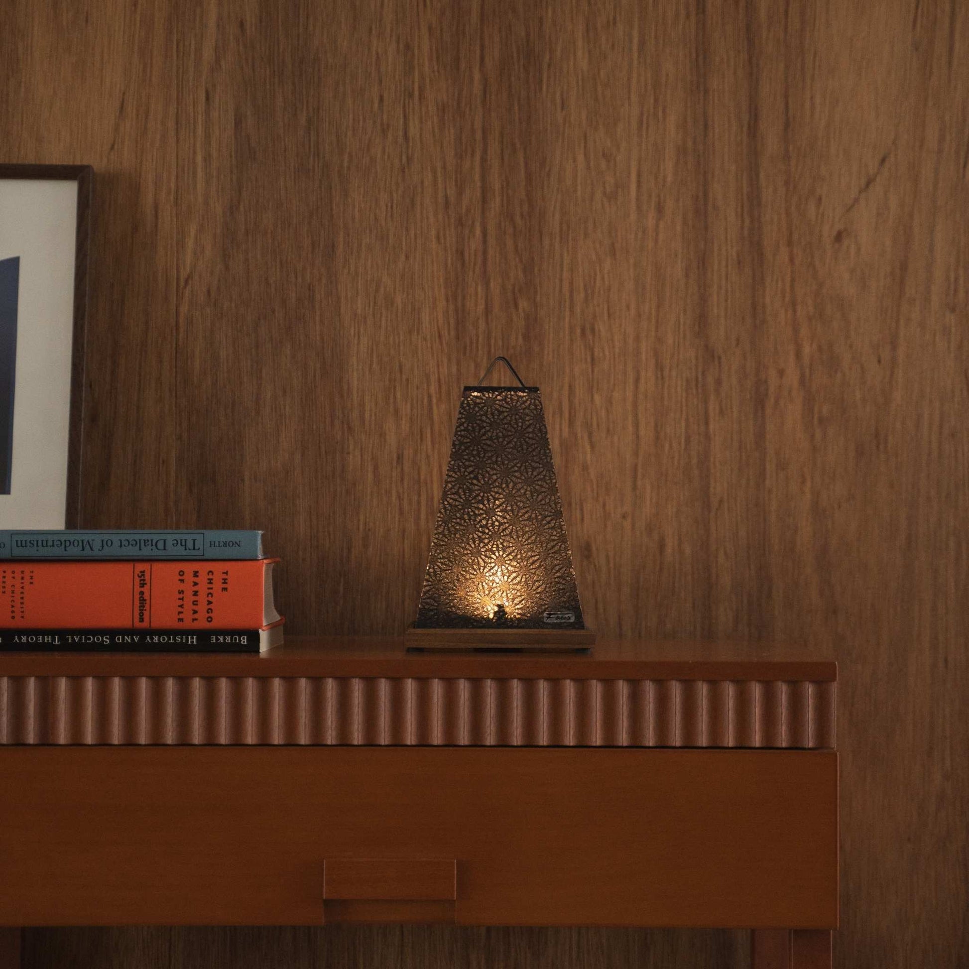 Lit Japanese paper table lamp "Mini Akari" Black acting as a soft ambient lamp on a mid-century modern console table.