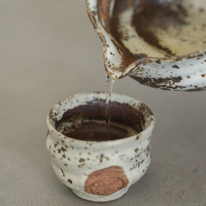 Close-up of the Zui white Japanese sake pitcher and ochoko cups on a wooden surface, adding timeless elegance to the room
