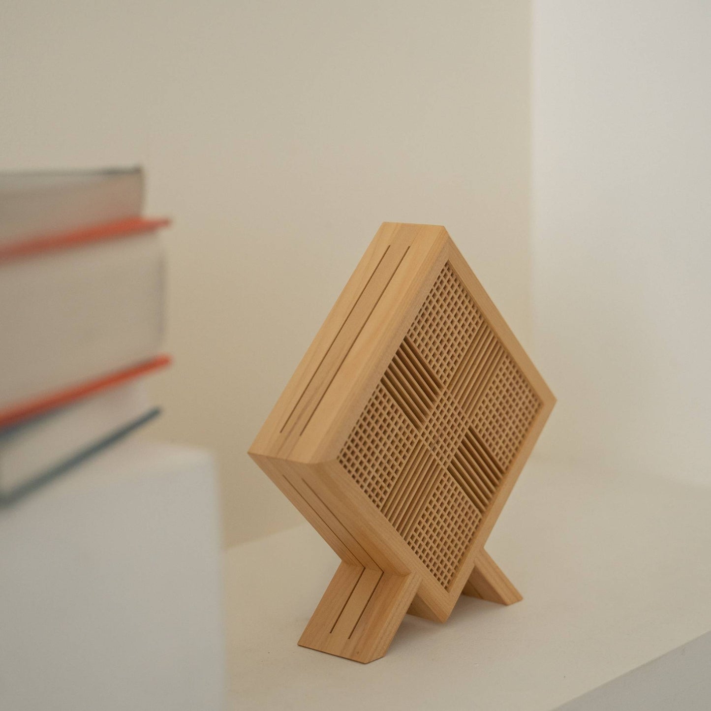 Close-up of unlit Japanese wood table lamp "Kanata" revealing fine Kumiko woodworking and its unique diamond shape on a Japandi style console table.