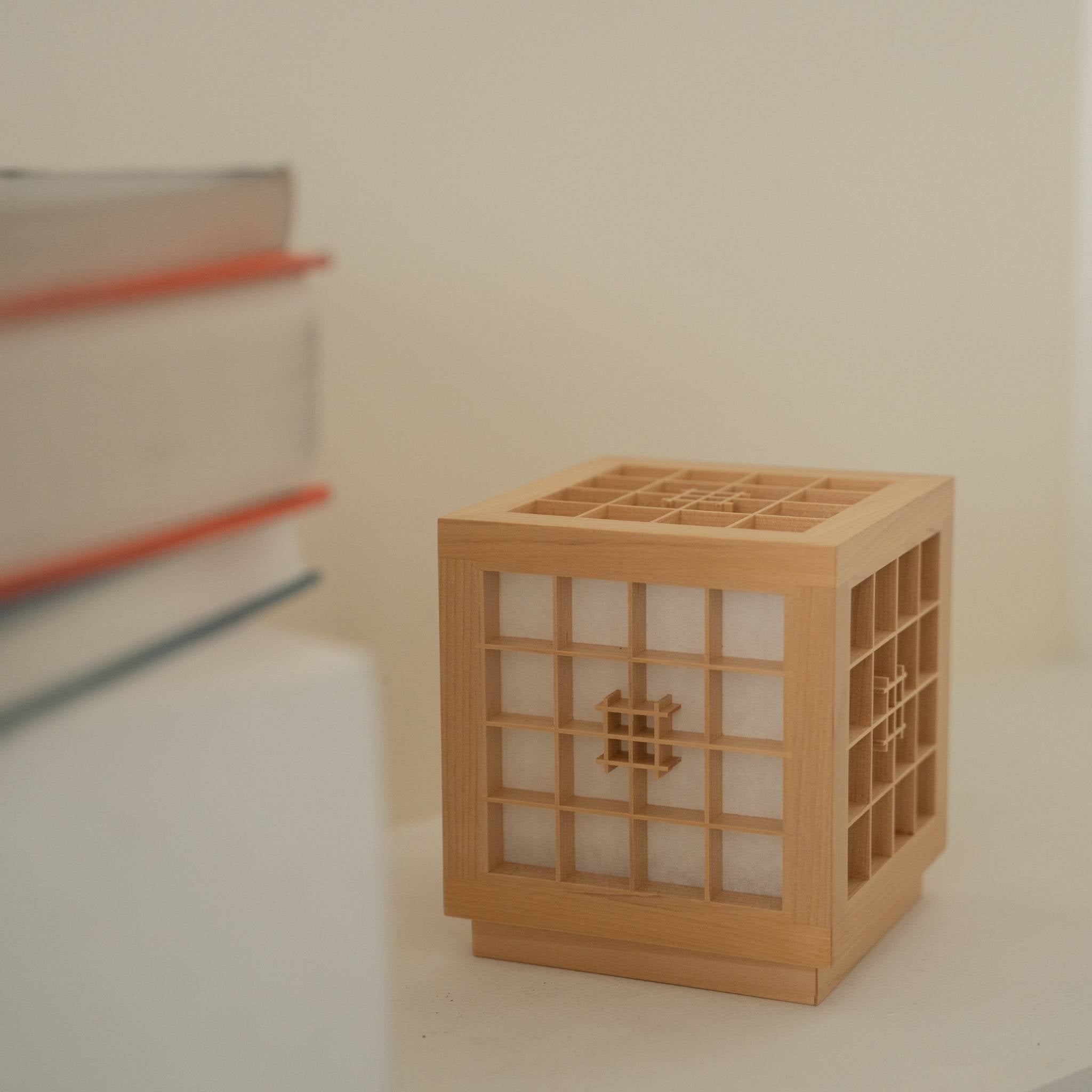 Japanese Wood Table Lamp "Honoka" showing detailed Kumiko woodworking next to books as a handcrafted decor accent.