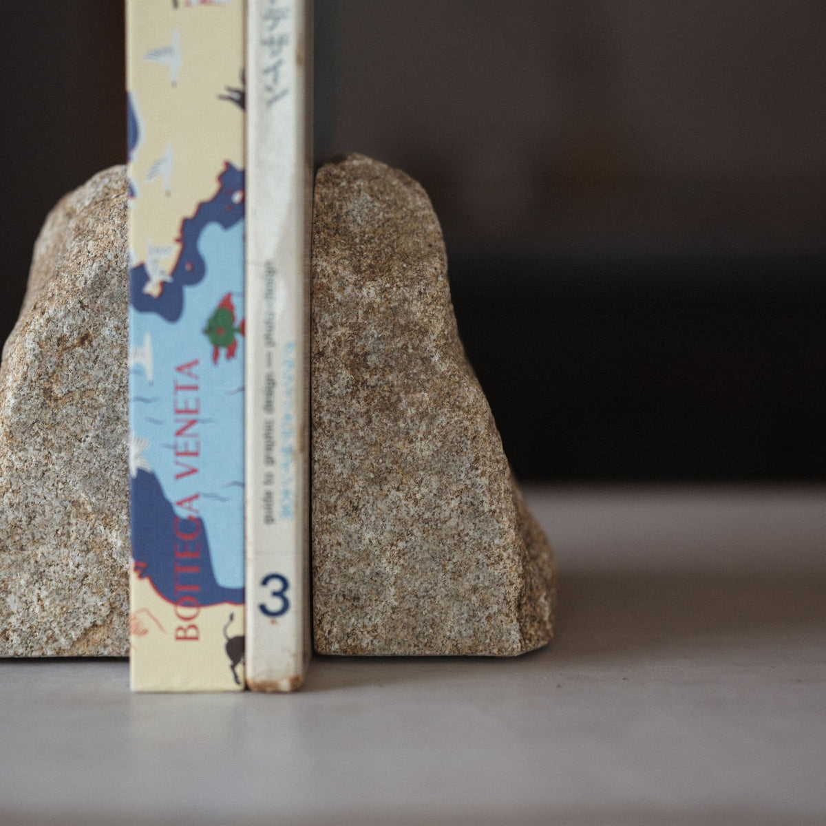 Close-up shot of a handcrafted Japanese Aji stone bookend holding several minimalist design books together.