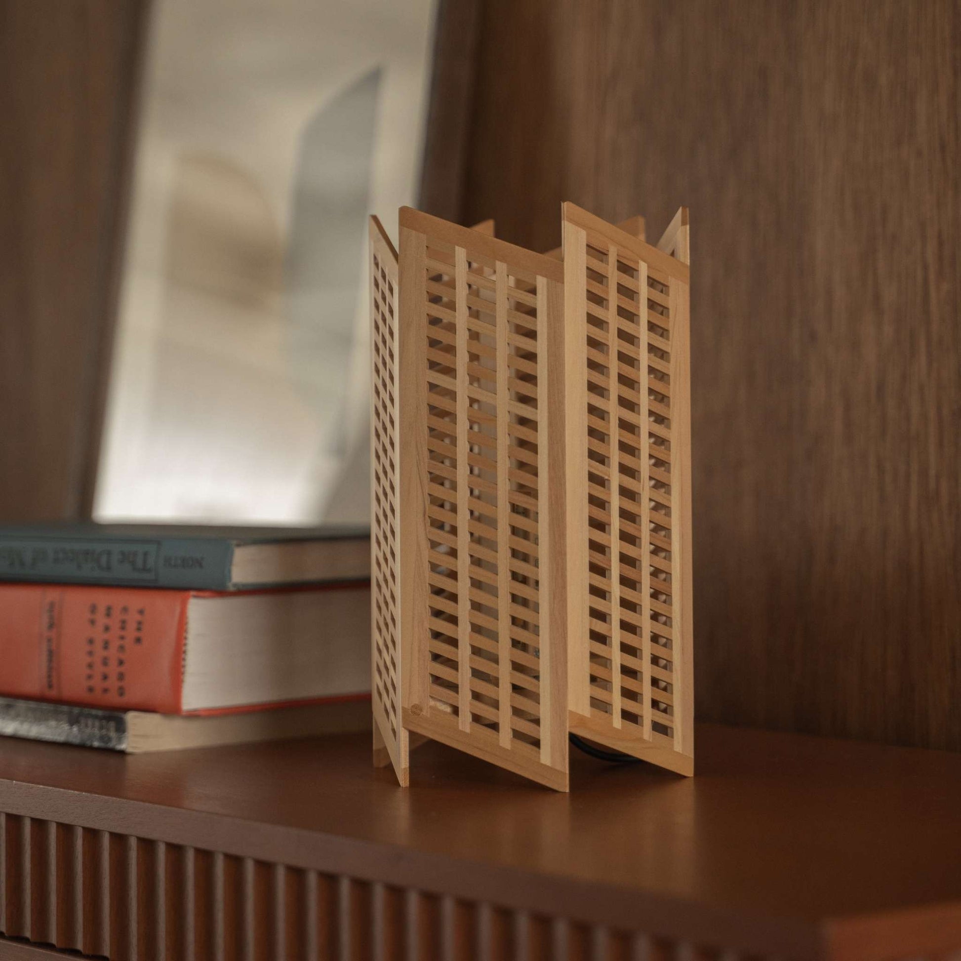 Nahaufnahme einer japanischen Holz-Tischlampe "Towaru", die präzise Kumiko-Holzarbeiten auf einem Konsolentisch als Wabi-Sabi-Dekoration zeigt.