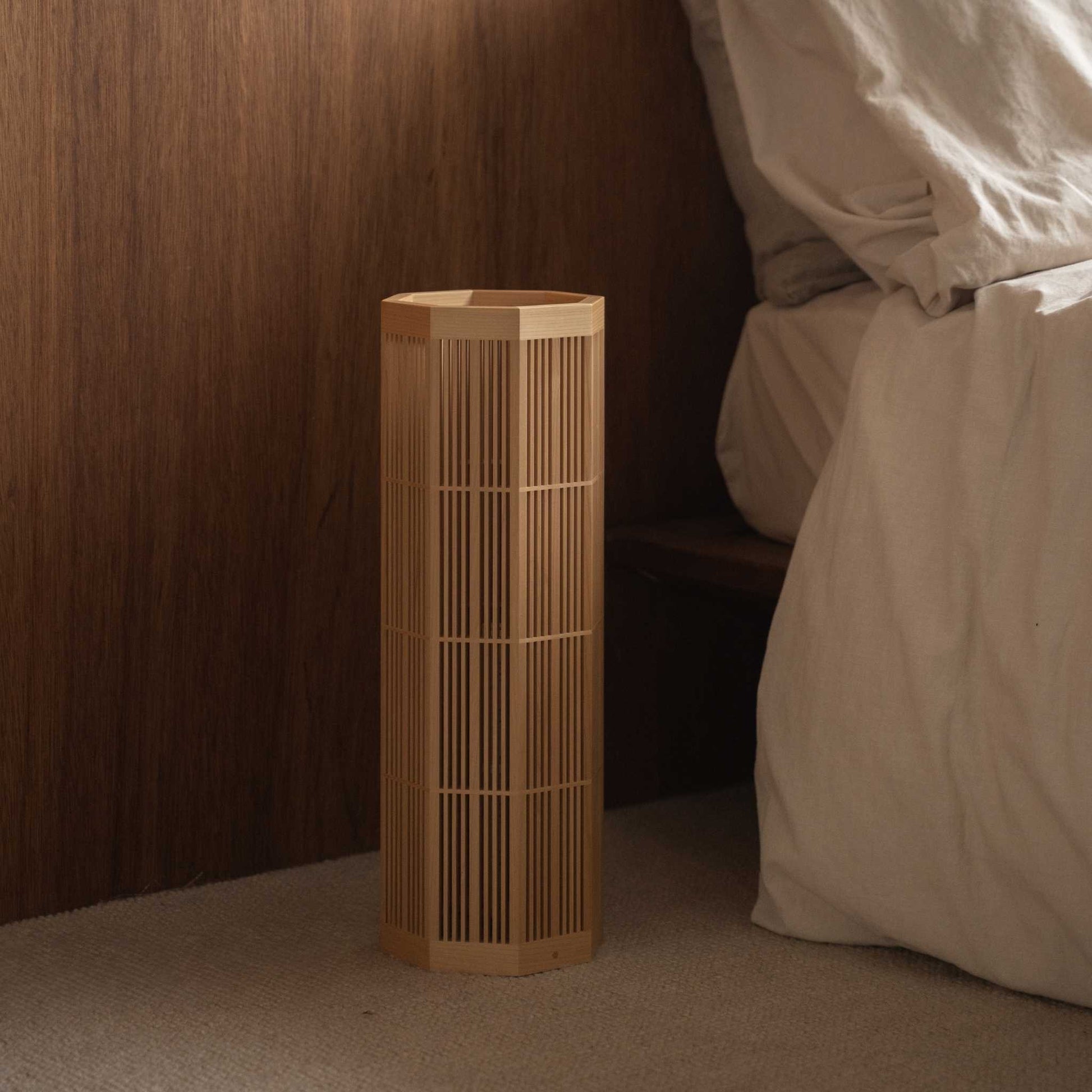 "Lampe sur pied japonaise "SAN" Grand modèle non allumée, présentant un bel artisanat Kumiko à côté d'un lit dans une chambre Japandi."