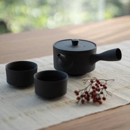 Black Japanese teapot and Japanese tea cups on a linen mat for tea lovers creating a serene modern aesthetic.