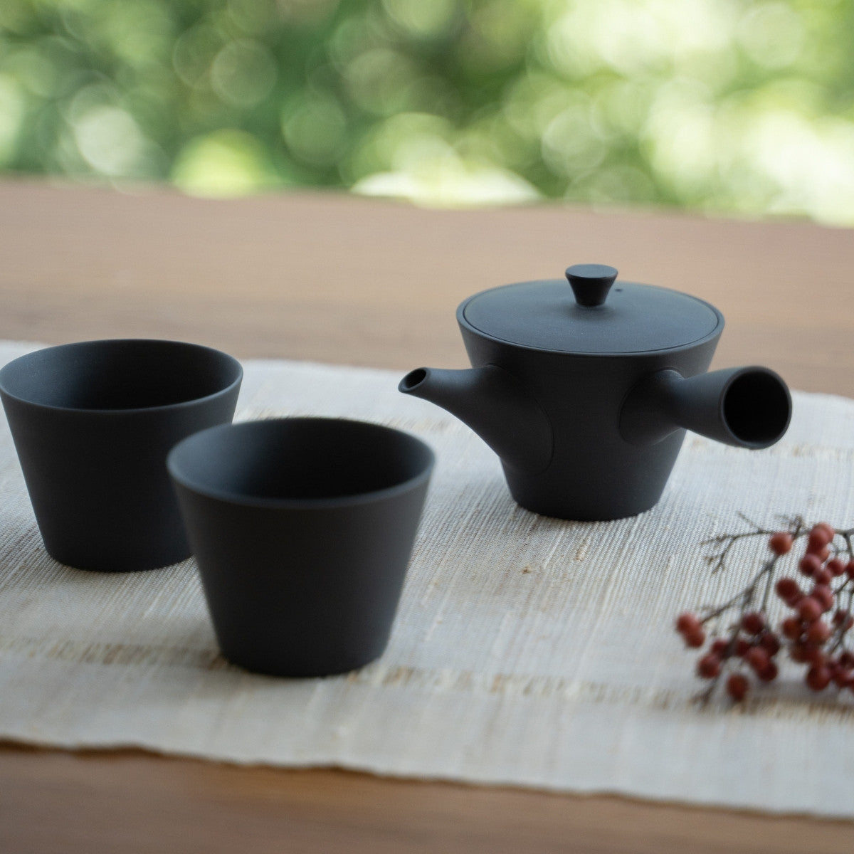 Schwarze japanische Teekanne "Sencha" und japanische Teetassen auf einem Tisch für Teeliebhaber, die einen modernen Zen-Moment genießen.