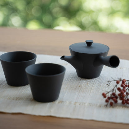 Schwarze japanische Teekanne "Sencha" und japanische Teetassen auf einem Tisch für Teeliebhaber, die einen modernen Zen-Moment genießen.