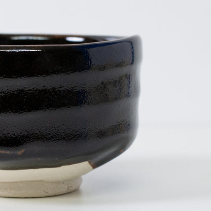 Tæt på detalje af sort matcha chawan-skål, der viser den unikke "Yuzu"-tekstur og ru Shino-lerbase for en wabi sabi-æstetik.