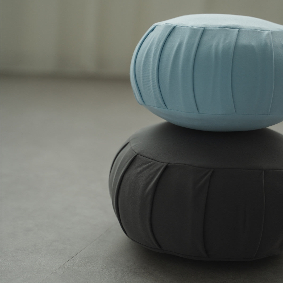 Calm blue and charcoal grey Japanese meditation cushion zafu, stacked in a modern space for a peaceful zen practice.