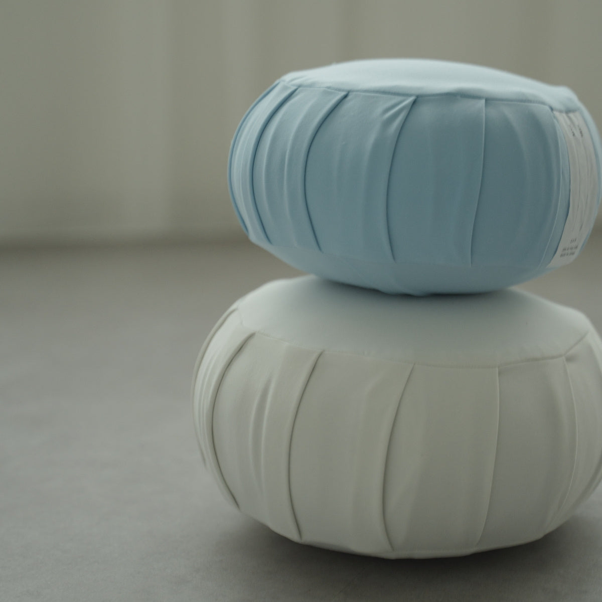 Coussin de méditation japonais zafu bleu calme et blanc clair de lune, empilé sur un sol moderne pour un yoga familial relaxant.
