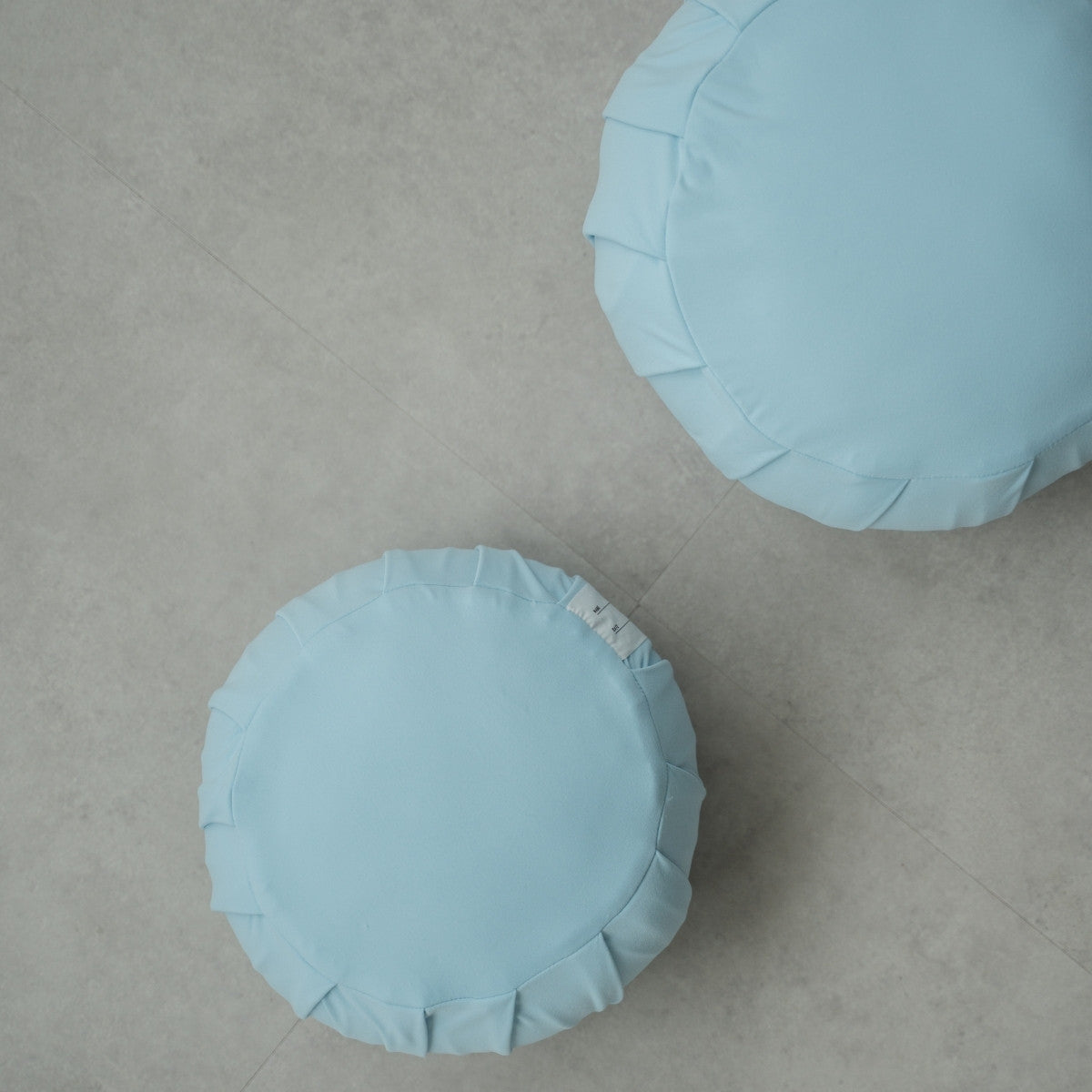 Twee rustige blauwe Japanse meditatiekussens (zafu), op een moderne grijze vloer, opgesteld voor een gedeelde familiezensessie.