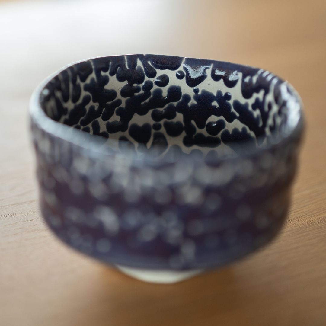 Tæt visning af interiøret i en japansk matcha-skål, med det mørke 'Midnight Blue' Kairagi-glasurmønster mod en hvid base, der fremhæver den revnede wabi sabi-tekstur.