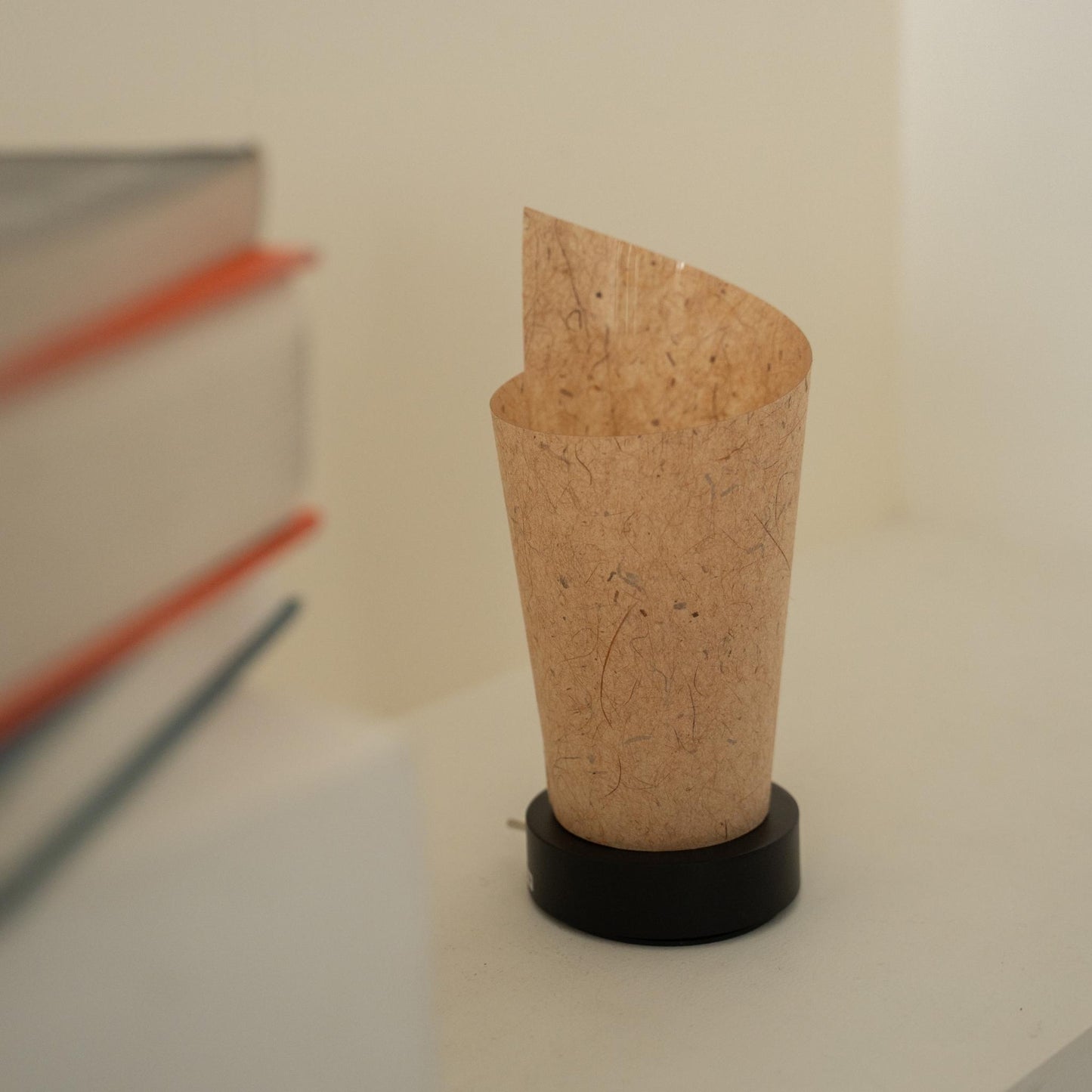 Gros plan d'une lampe de table japonaise non allumée "Maki" en écorce de cèdre, mettant en valeur son design roulé et sa texture de papier naturelle pour une décoration wabi sabi.