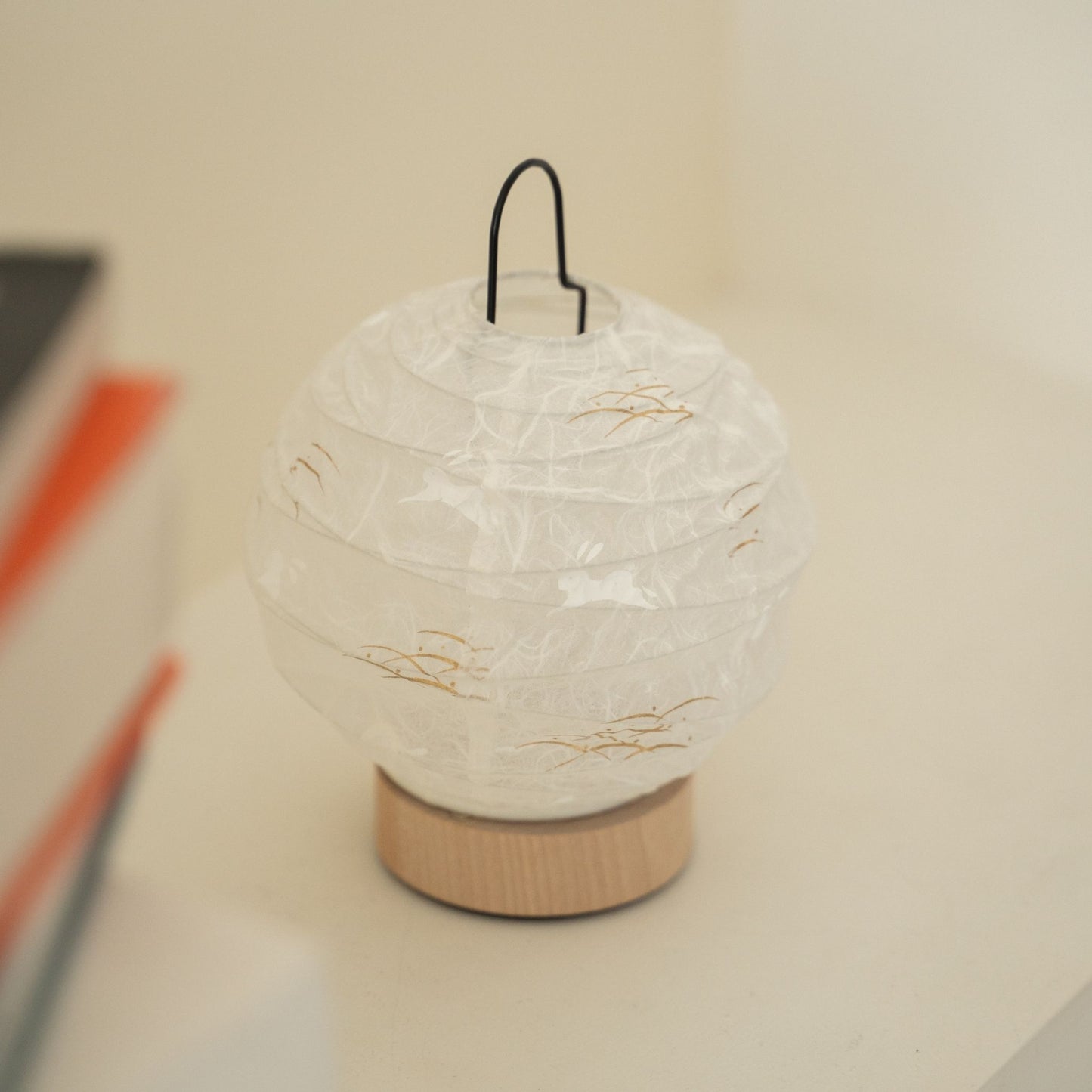 Close-up of an unlit round Japanese paper table lamp "Yuhi" Rabbit showcasing its textured paper surface for wabi sabi decor on a Japandi living room console table.