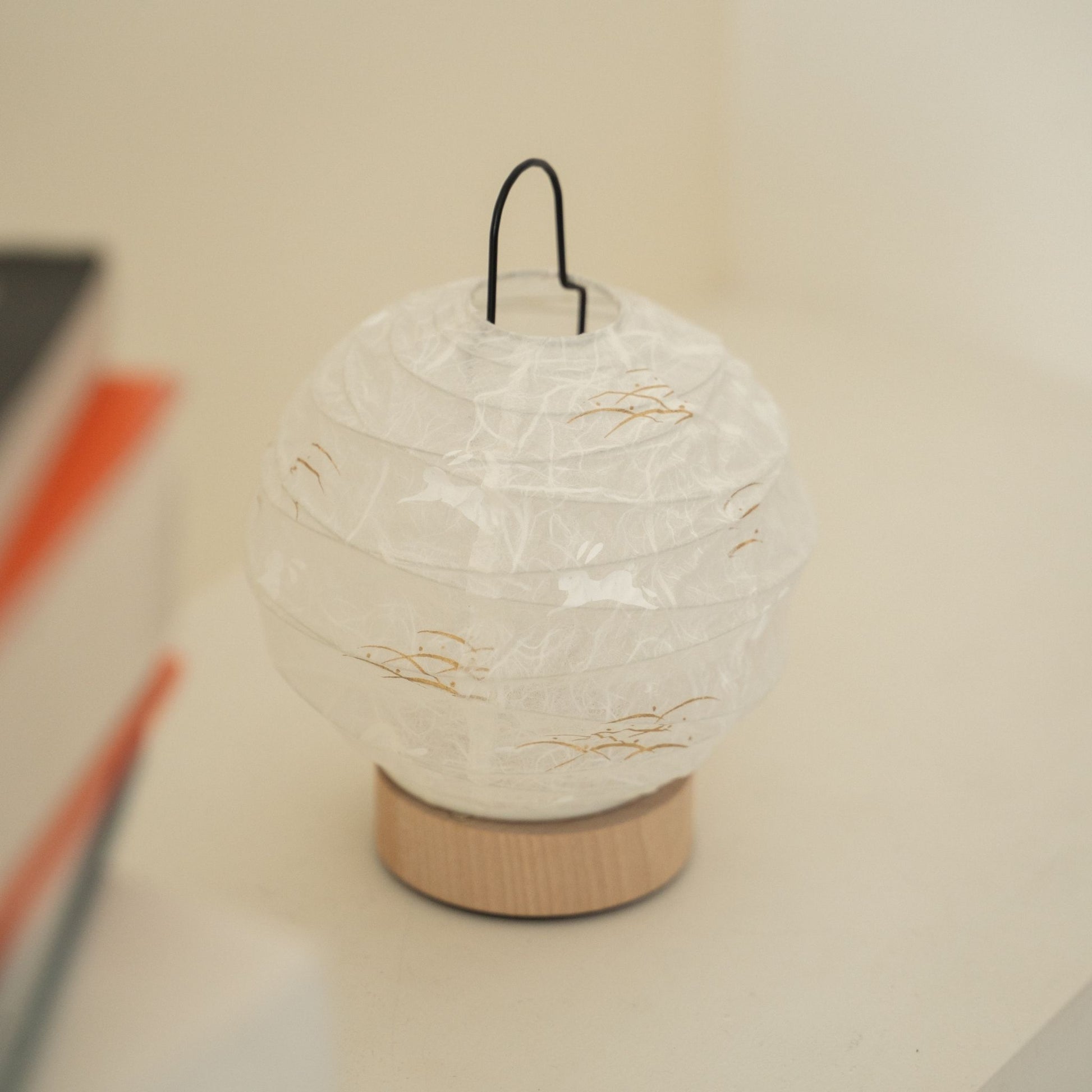 Close-up of an unlit round Japanese paper table lamp "Yuhi" Rabbit showcasing its textured paper surface for wabi sabi decor on a Japandi living room console table.