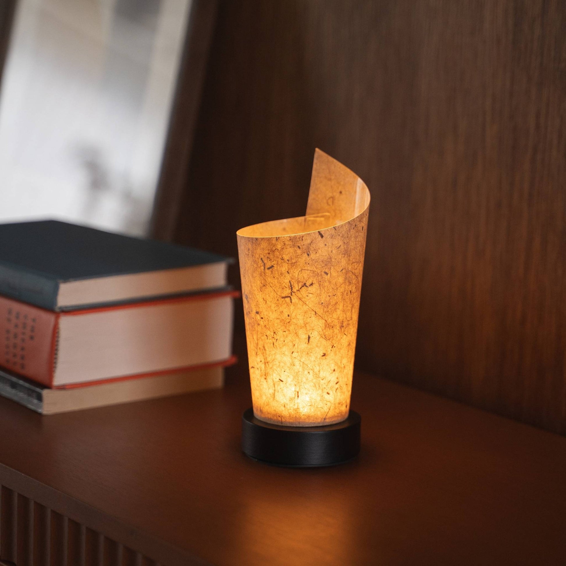 Gros plan d'une lampe de table japonaise en papier allumée "Maki" Écorce de cèdre servant de lampe d'appoint chaleureuse avec une texture de papier délicate et une base en bois.