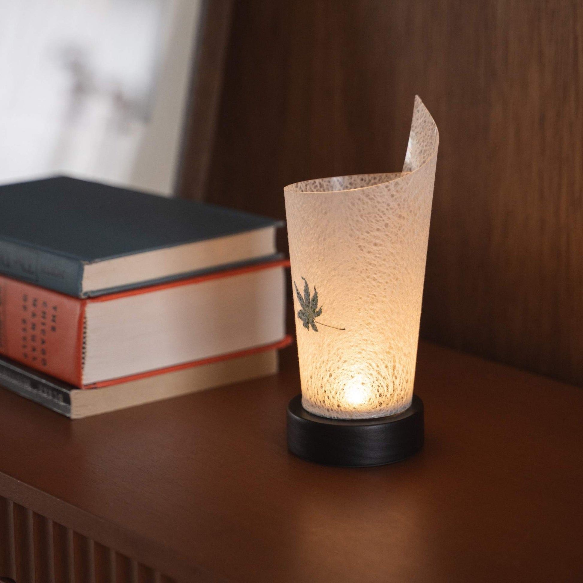 Gros plan d'une lampe de table japonaise en papier allumée "Maki" Feuille d'érable Momiji servant de lampe d'appoint chaleureuse avec une texture de papier délicate et une base en bois.