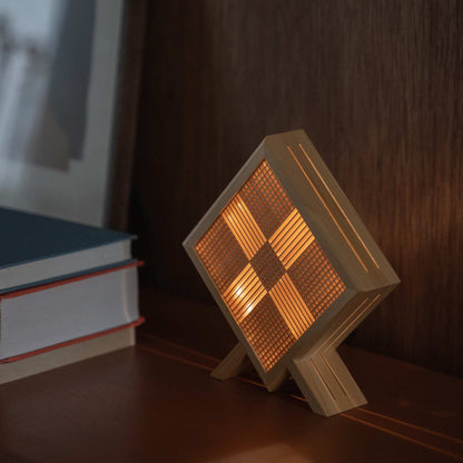 Glowing Japanese wood table lamp "Kanata" projecting a luminous X shape as an ambient lamp on a mid-century modern style console.