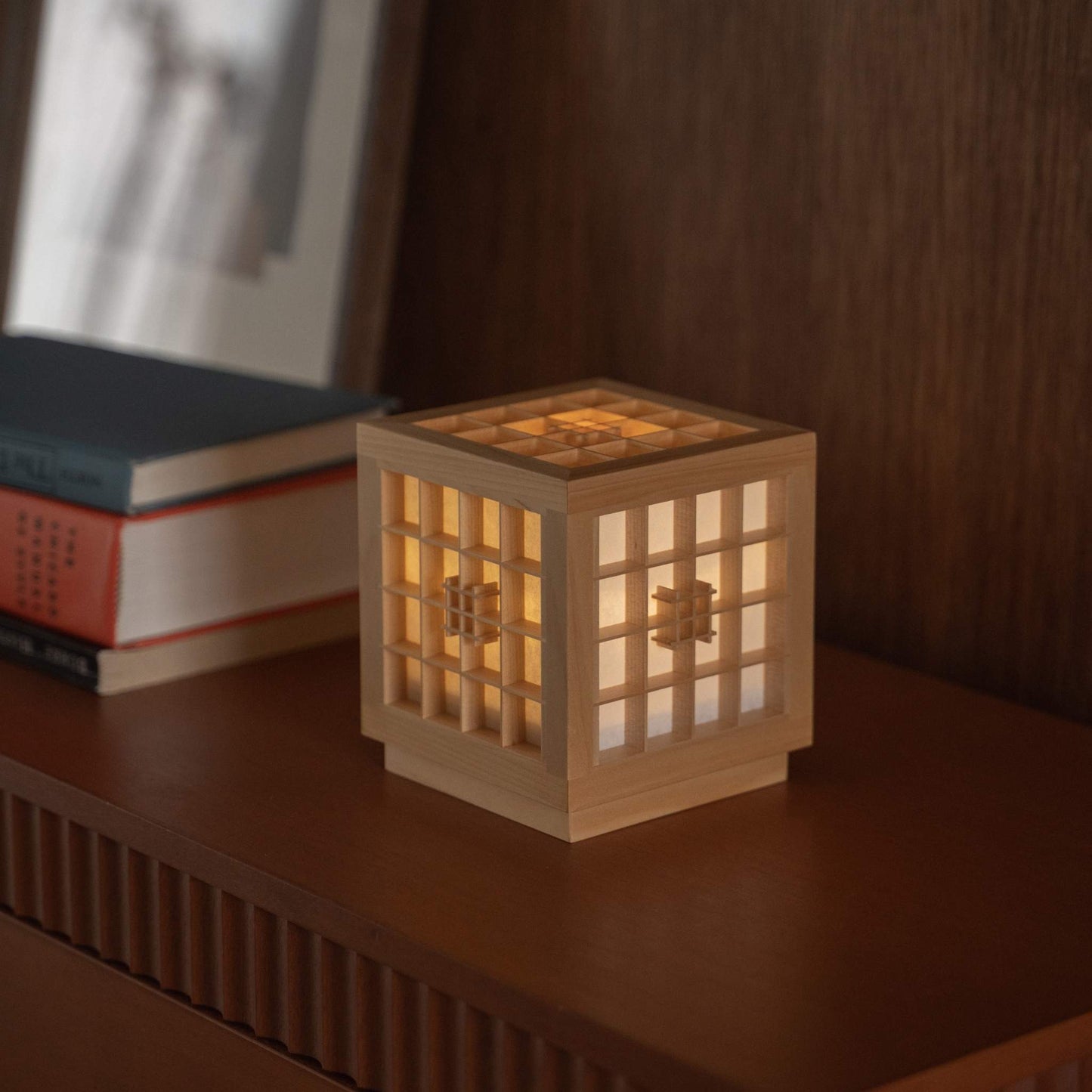 Glowing Japanese Wood Table Lamp "Honoka" serving as a cozy ambient lamp next to books on a wooden console table.