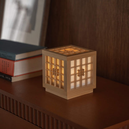 Glowing Japanese Wood Table Lamp "Honoka" serving as a cozy ambient lamp next to books on a wooden console table.