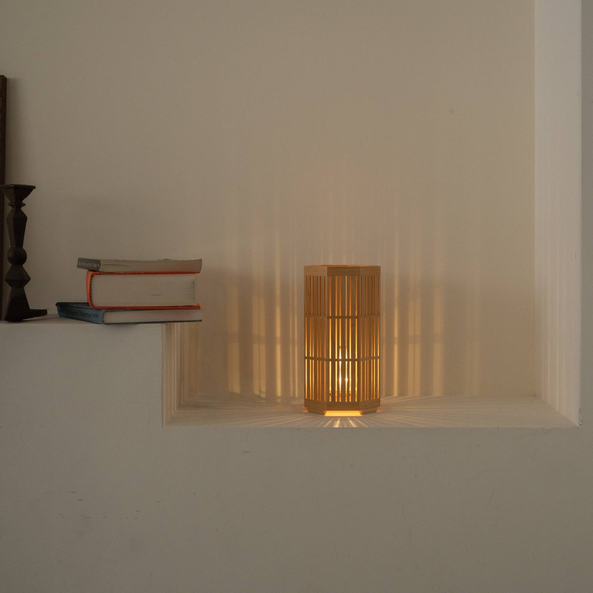 Lit Japanese wood table lamp "Kagayaki" casting beautiful radial shadows as a wabi sabi accent lamp in a Japandi living room.