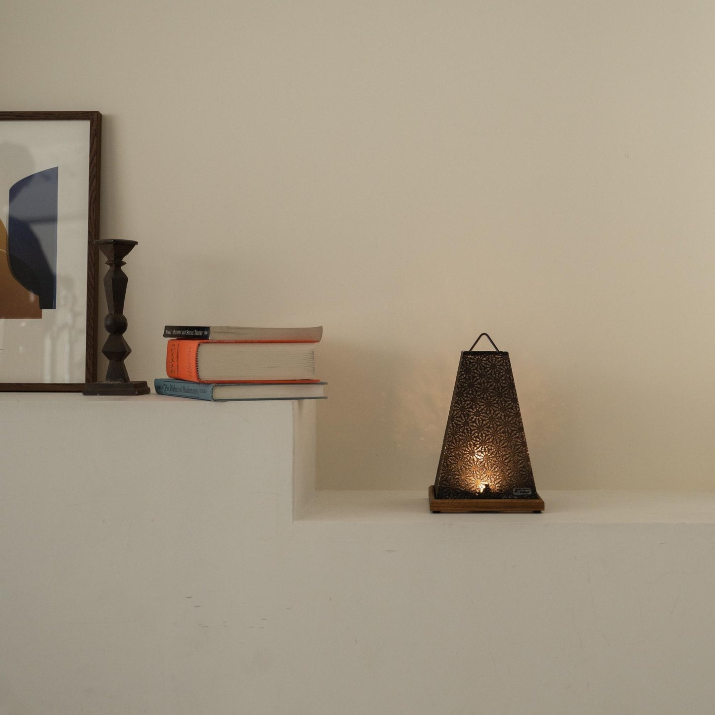 Lit Japanese paper table lamp "Mini Akari" Black casting a warm glow as an accent lamp on a white Japandi living room console.
