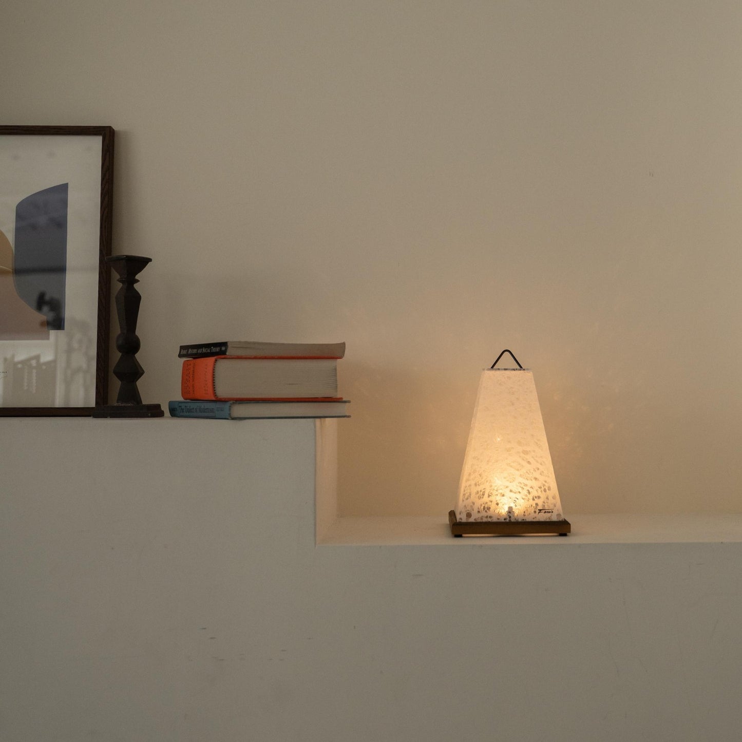 Lit Japanese paper table lamp "Mini Akari" White casting a warm glow as an accent lamp on a white Japandi living room console.