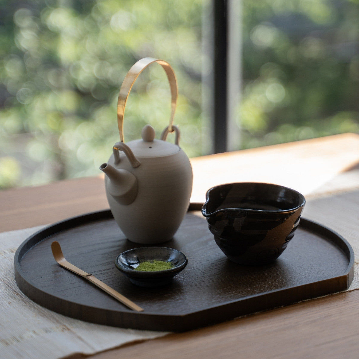Sumi Black japansk matcha skål og tekande med tud, på et træfad ved et solbeskinnet vindue, klar til et moderne matcha latte ritual.