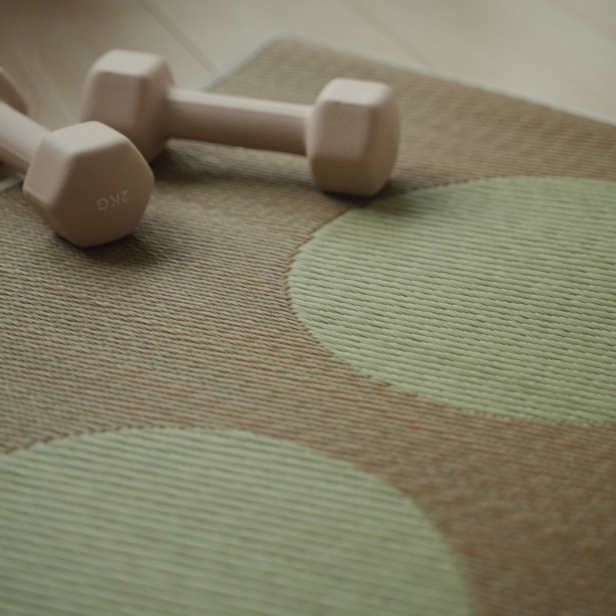 Gedetailleerd beeld van Japanse Tatami Yoga Mat "Maan" Beige natuurlijke zeegras weefpatroon en een kleine halter.