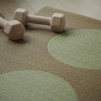 Gedetailleerd beeld van Japanse Tatami Yoga Mat "Maan" Beige natuurlijke zeegras weefpatroon en een kleine halter.