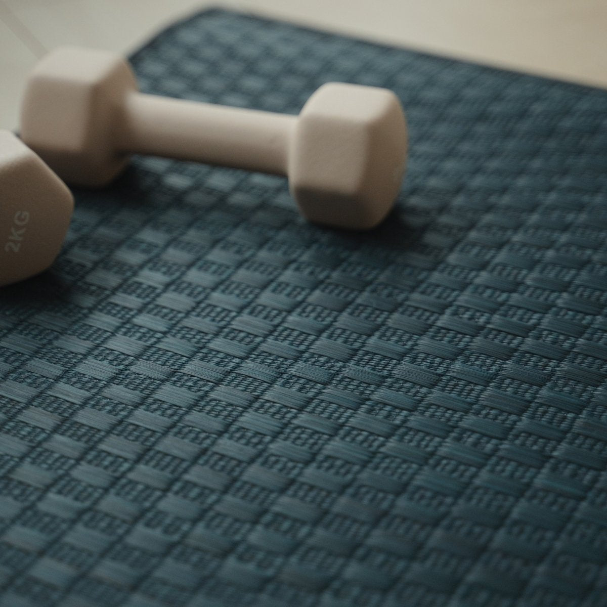 Bovenaanzicht van de Japanse Tatami Yoga Mat "Ed Plain" Navy met dumbbells, met de nadruk op de strakke weving en donkere rand.