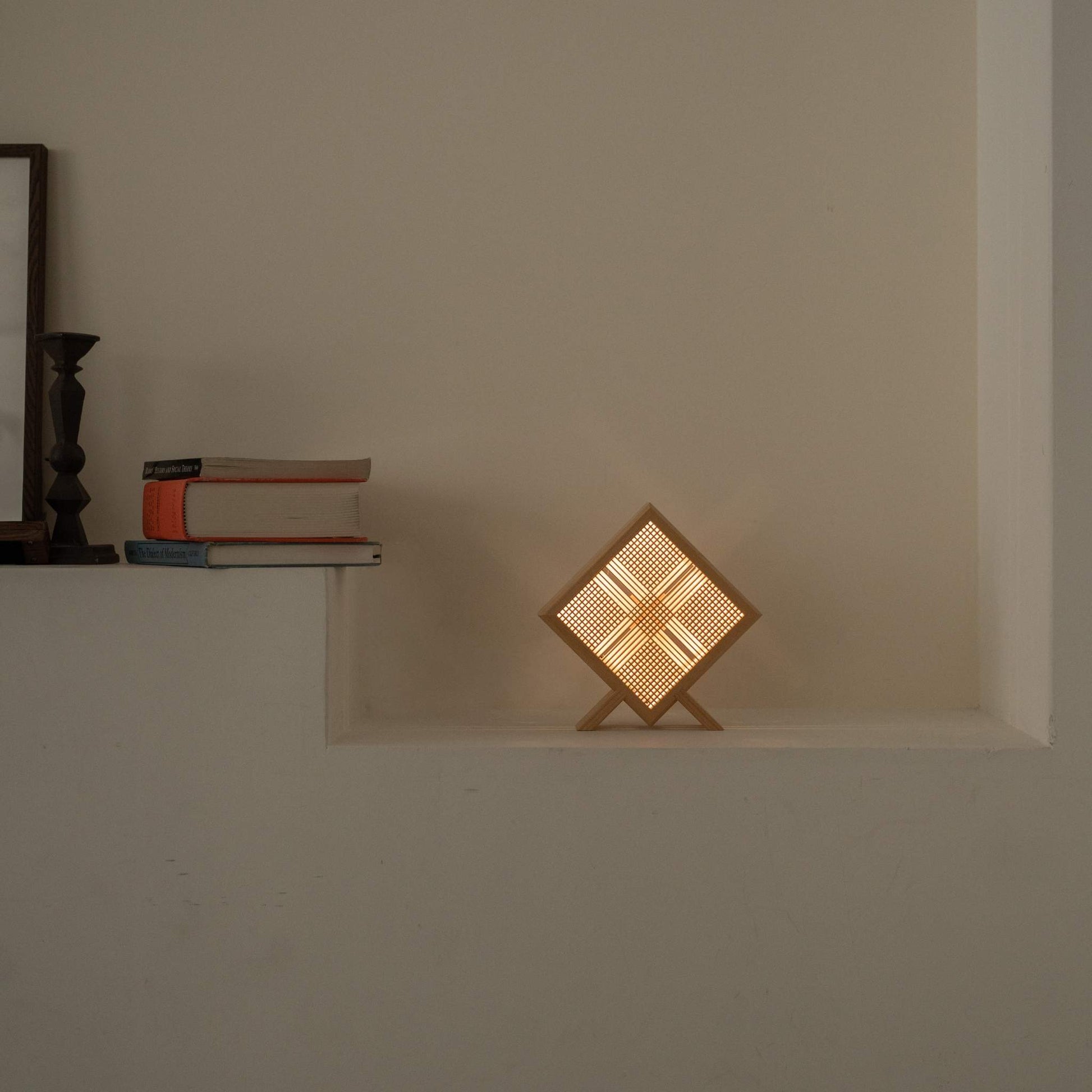Glowing Japanese wood table lamp "Kanata" serving as an ambient lamp on a white console table in a Japandi living room.