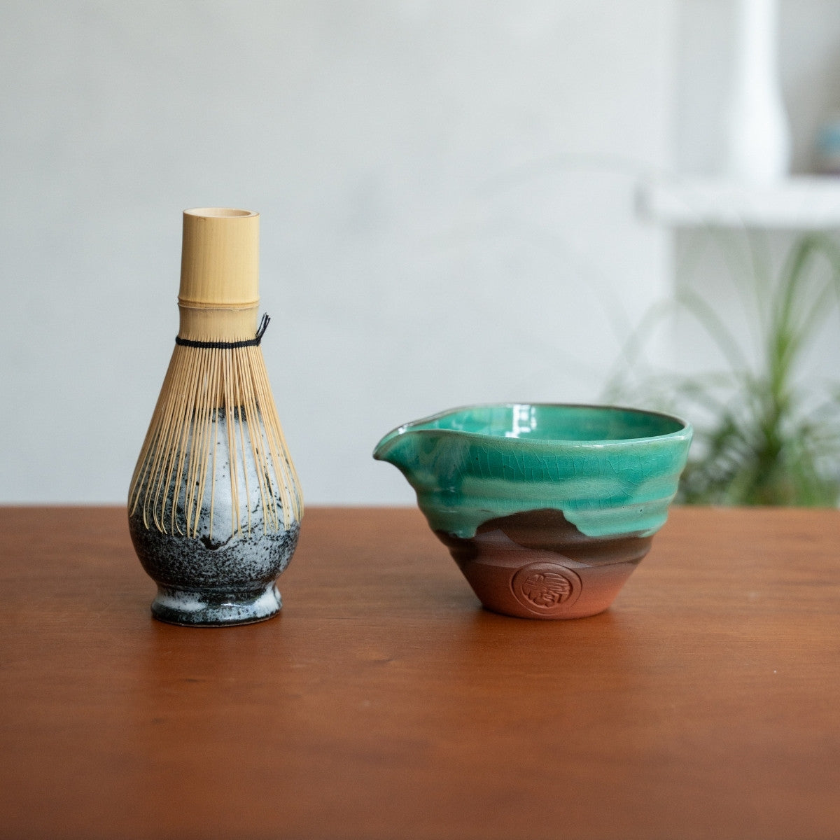 Japansk matcha-piskeris-holder og smaragdgrøn matcha-skål med tud på et træbord, klar til et dagligt morgen-te-ritual.