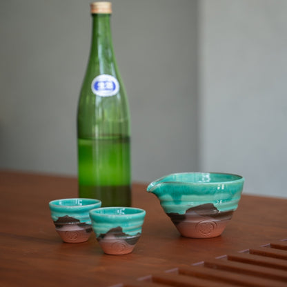 Emerald green Japanese sake set (sake carafe, two cups) on a wood table, ready to bring elegance to a special dinner.