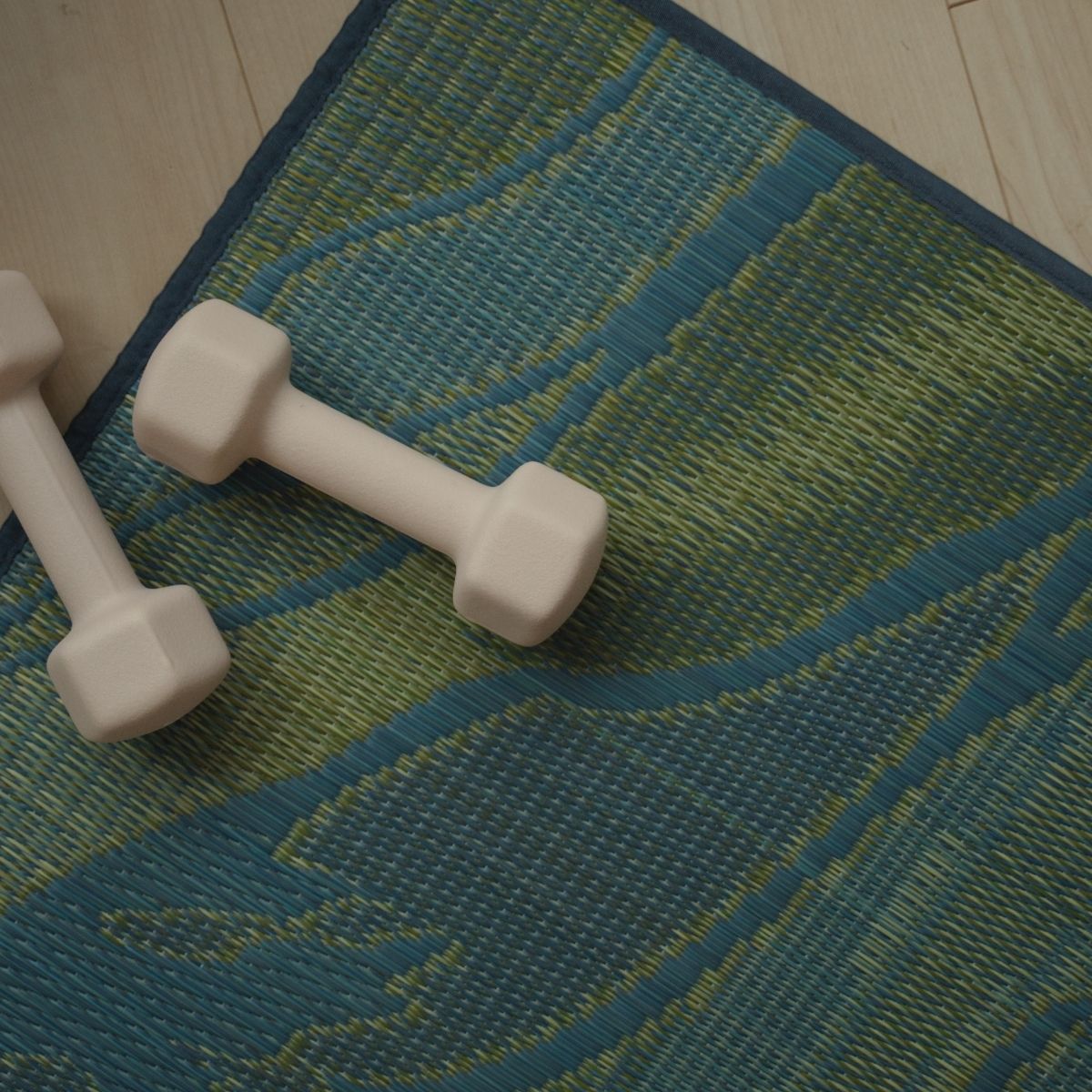 Overhead view of the Japanese Tatami Yoga Mattress "Marble" Blue on a wooden floor with two dumbbells for home fitness