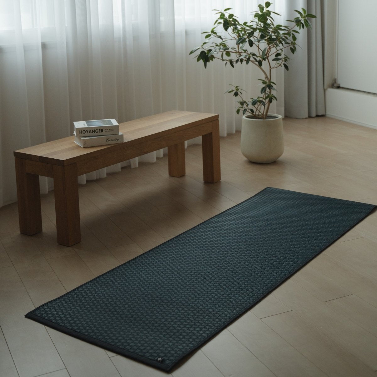 Japanse Tatami Yogamat "Ed Plain" Navy uitgerold op een houten vloer in een minimalistische woonkamer voor een serene thuisoefening.